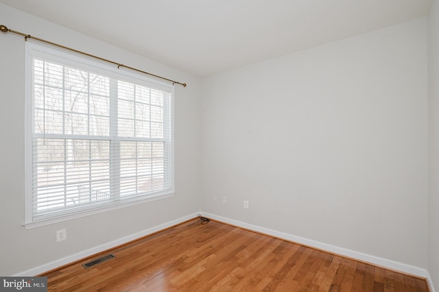 empty room with visible vents, baseboards, and wood finished floors