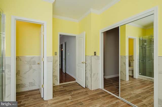 hallway featuring a wainscoted wall, crown molding, tile walls, and wood finish floors