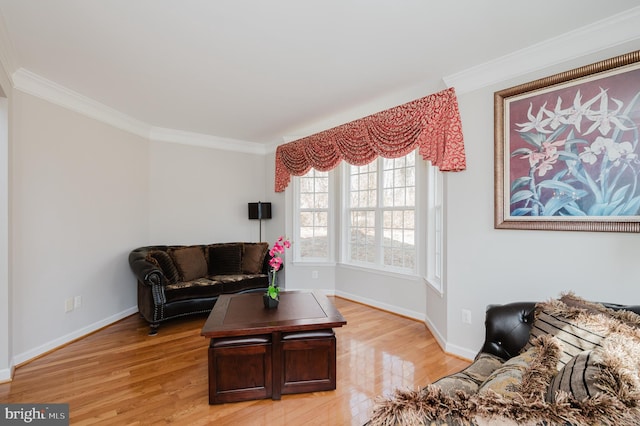 living area with ornamental molding, light wood-style flooring, and baseboards