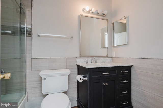 bathroom with toilet, a wainscoted wall, tile walls, and vanity