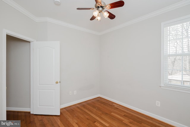 empty room featuring a ceiling fan, crown molding, baseboards, and wood finished floors