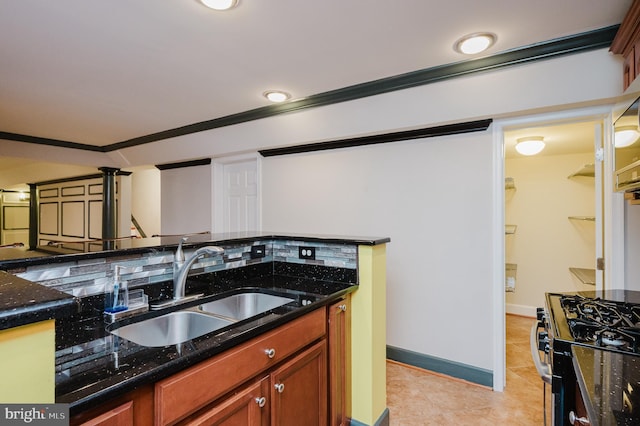 kitchen featuring light tile patterned flooring, a sink, baseboards, stainless steel range with gas cooktop, and dark stone counters