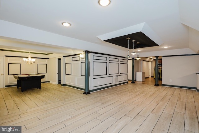 interior space with light wood-style flooring, a breakfast bar, a kitchen island, baseboards, and hanging light fixtures