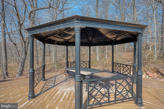 wooden terrace featuring outdoor dining area and a gazebo