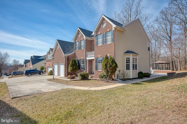 view of front of home with driveway, brick siding, a front yard, and a gazebo