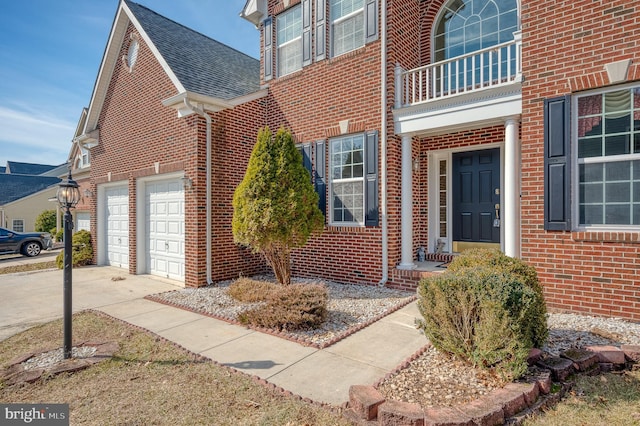 property entrance with concrete driveway, brick siding, roof with shingles, and a balcony