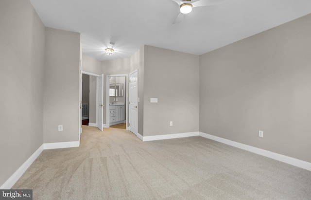 unfurnished bedroom featuring a ceiling fan, light carpet, baseboards, and ensuite bathroom