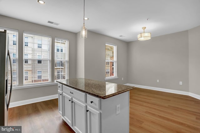 kitchen featuring wood finished floors, visible vents, white cabinets, baseboards, and stainless steel fridge with ice dispenser