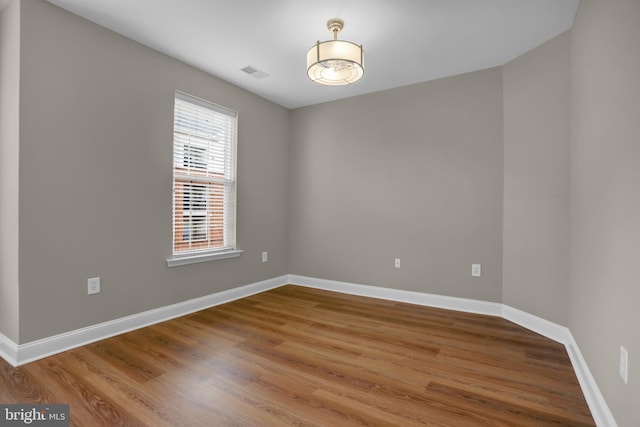 spare room featuring visible vents, baseboards, and wood finished floors