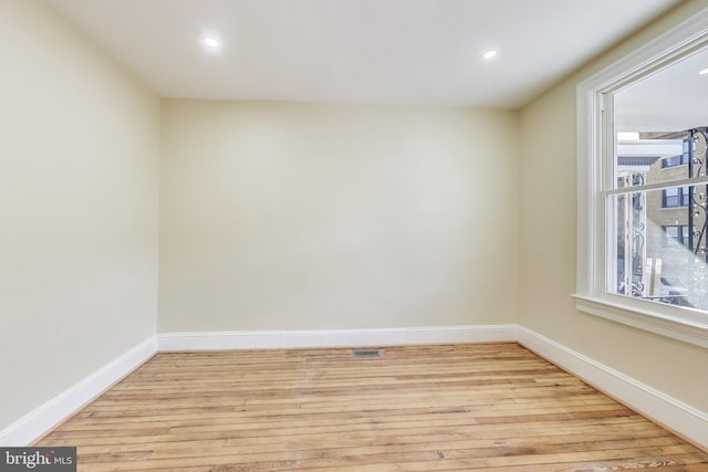 spare room featuring visible vents, light wood-style flooring, a wealth of natural light, and baseboards