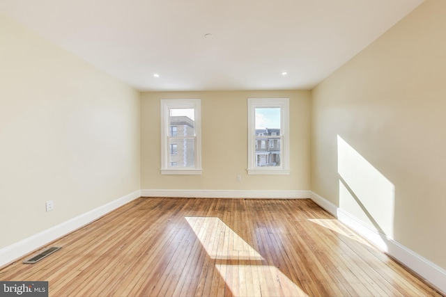 empty room featuring light wood-style floors, baseboards, and visible vents