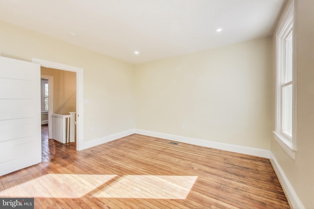 empty room featuring recessed lighting, hardwood / wood-style flooring, and baseboards