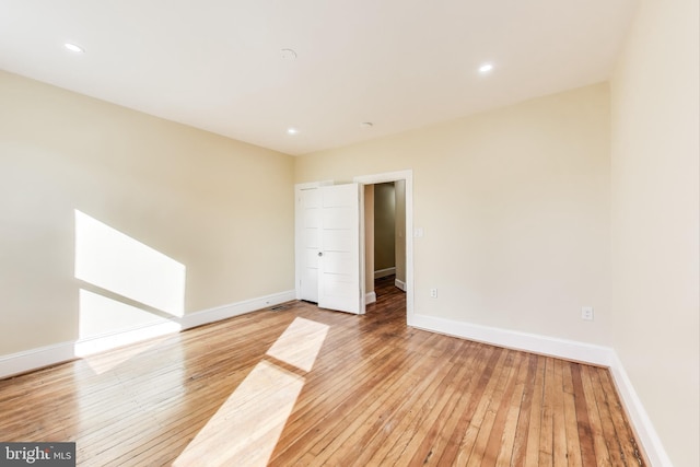 empty room with recessed lighting, light wood-type flooring, and baseboards