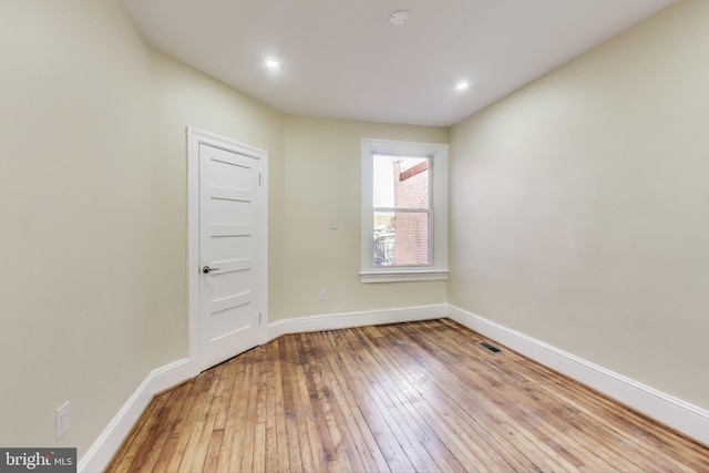 spare room featuring light wood-type flooring, visible vents, and baseboards