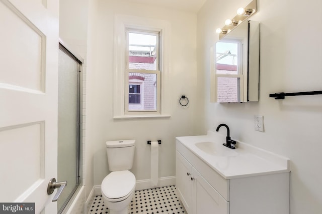 bathroom featuring baseboards, a shower with shower door, vanity, and toilet