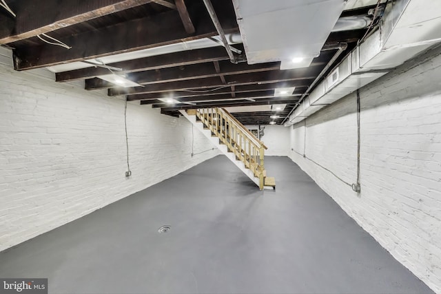 unfinished basement featuring stairway and brick wall