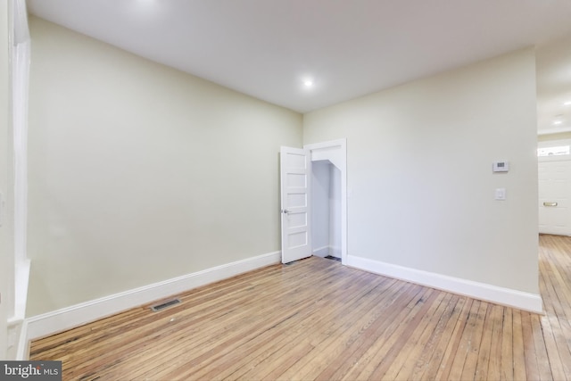 spare room with light wood-type flooring, visible vents, and baseboards