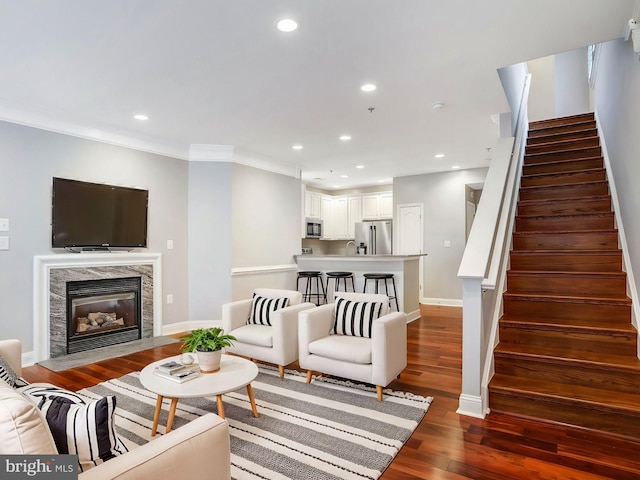 living area featuring recessed lighting, dark wood-type flooring, a premium fireplace, baseboards, and stairs