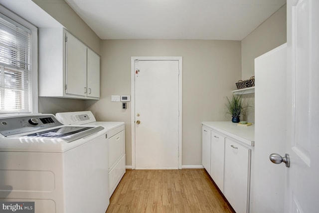 laundry area featuring light wood-type flooring, cabinet space, baseboards, and washing machine and clothes dryer