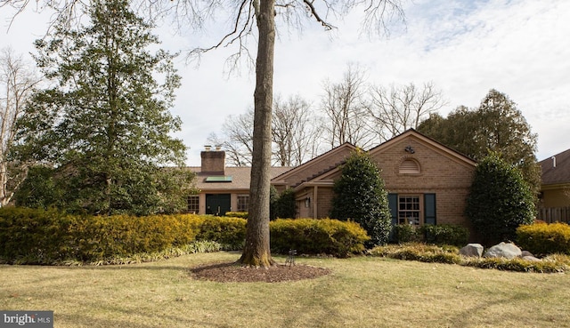 ranch-style house featuring brick siding, a front lawn, and a chimney