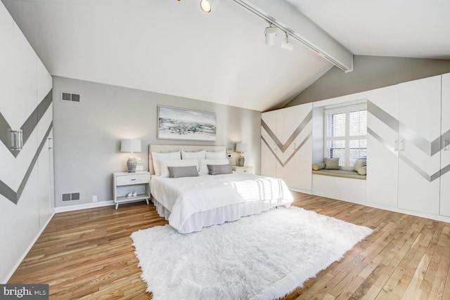 bedroom featuring lofted ceiling with beams, rail lighting, light wood-style flooring, and visible vents