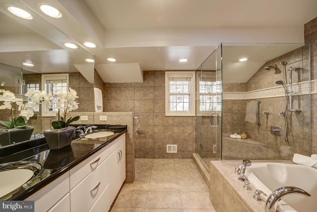 bathroom with visible vents, a sink, tile walls, and a shower stall