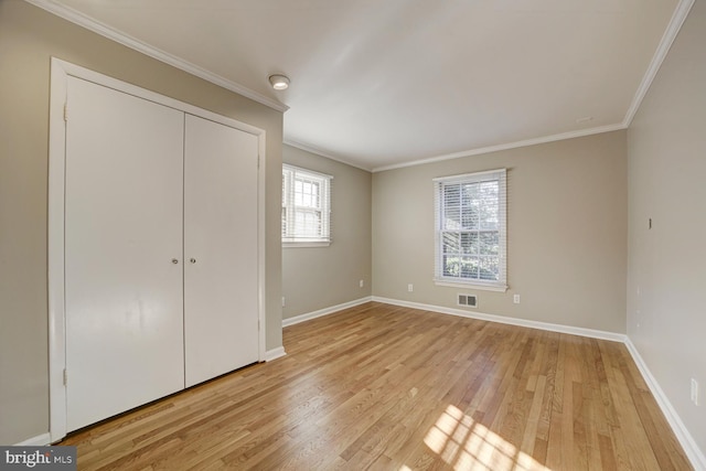 unfurnished bedroom featuring visible vents, baseboards, light wood-style floors, a closet, and crown molding