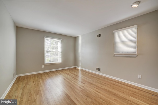 unfurnished room with light wood-style flooring, visible vents, and baseboards