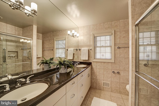 bathroom featuring a shower stall, a sink, visible vents, and tile walls