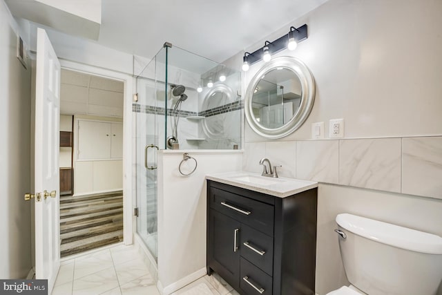 bathroom with marble finish floor, tile walls, toilet, a shower stall, and vanity