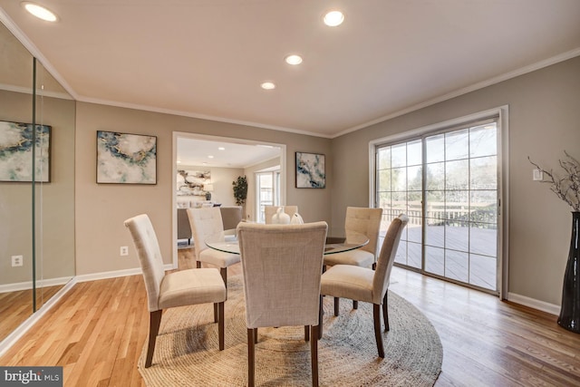 dining space featuring light wood-type flooring, baseboards, and crown molding