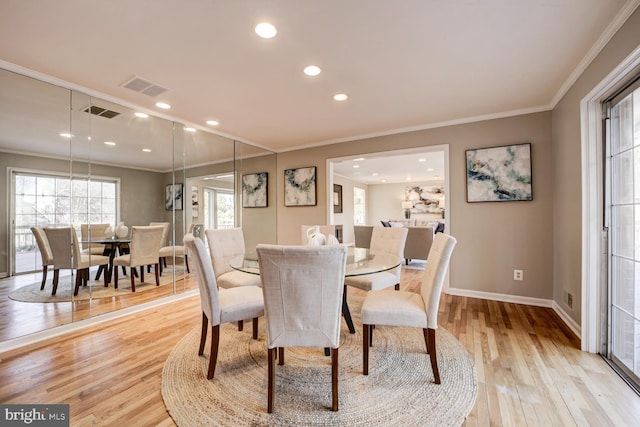 dining space with light wood finished floors, visible vents, and crown molding