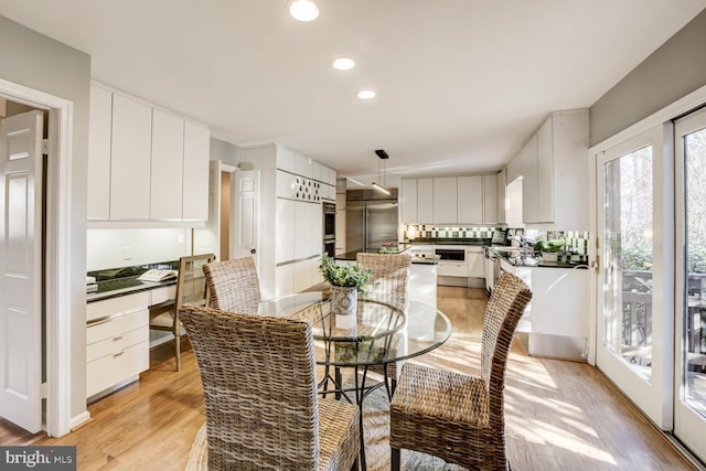 dining room with light wood finished floors, built in desk, and recessed lighting