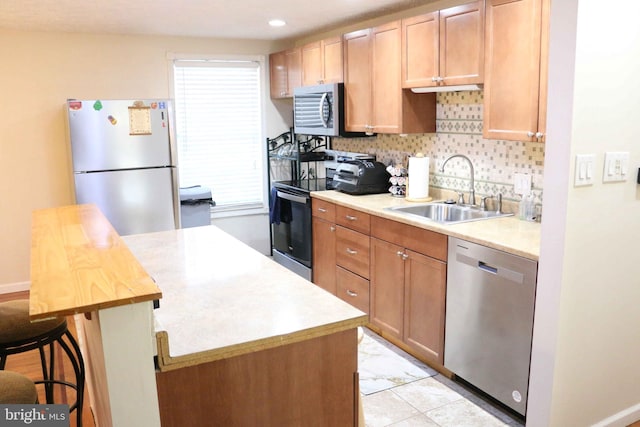 kitchen featuring appliances with stainless steel finishes, a sink, a center island, and decorative backsplash