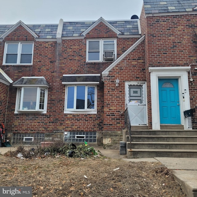 view of property with entry steps, brick siding, and a high end roof