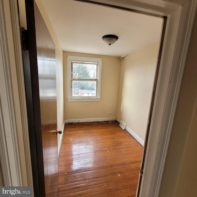 unfurnished room featuring light wood-type flooring, visible vents, and baseboards