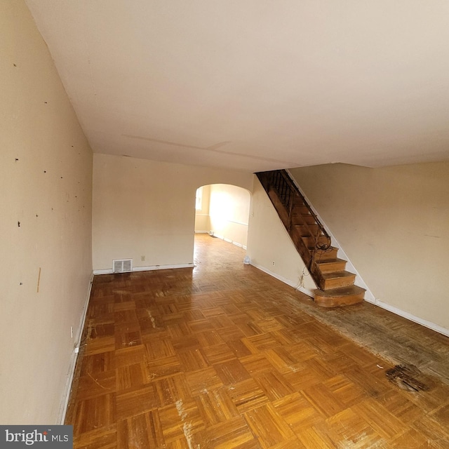 unfurnished room featuring arched walkways, visible vents, stairway, and baseboards