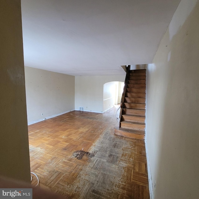 staircase with visible vents, arched walkways, and baseboards