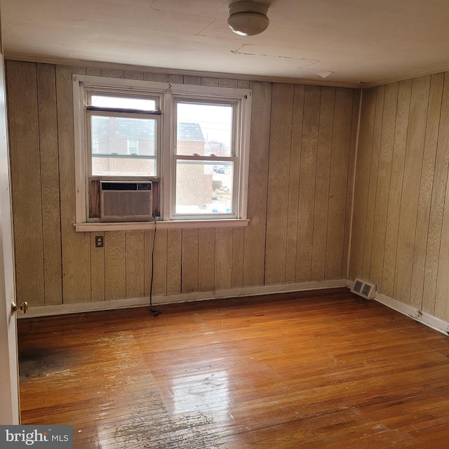 spare room featuring light wood-type flooring, cooling unit, visible vents, and baseboards