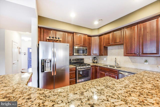 kitchen featuring stainless steel appliances, a sink, decorative backsplash, and light stone countertops