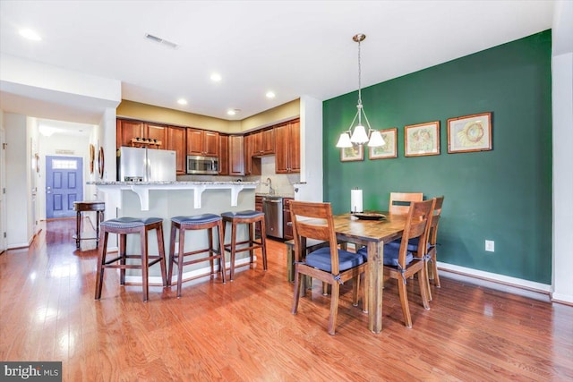 dining area featuring a notable chandelier, recessed lighting, visible vents, light wood-type flooring, and baseboards