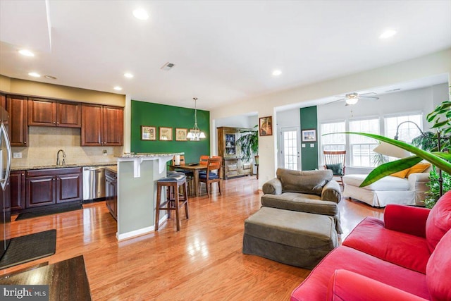 living area with a ceiling fan, recessed lighting, visible vents, and light wood finished floors