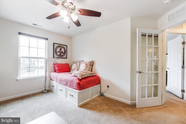 bedroom with baseboards, visible vents, a ceiling fan, and light colored carpet