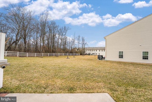 view of yard featuring central AC and fence