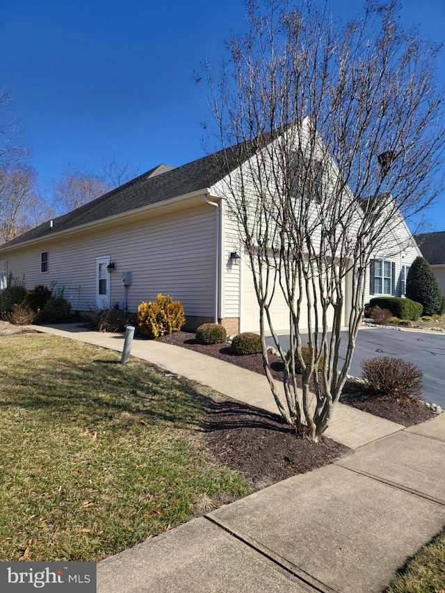 view of side of property featuring a yard, driveway, and an attached garage