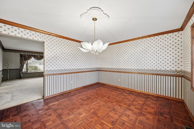 spare room with ornamental molding, wainscoting, an inviting chandelier, and wallpapered walls