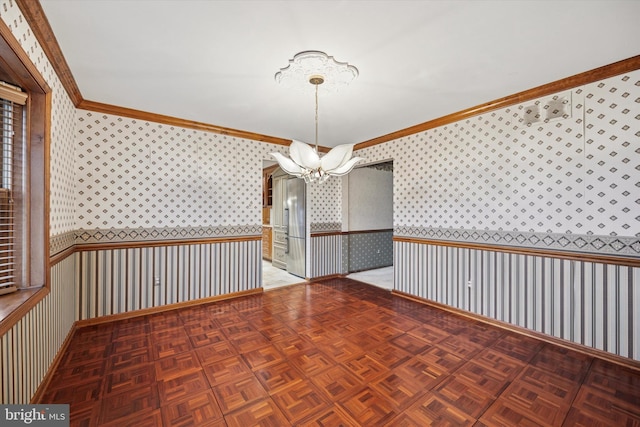 empty room featuring wallpapered walls, ornamental molding, a notable chandelier, and wainscoting