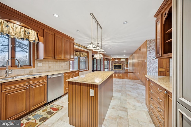 kitchen with a large fireplace, decorative backsplash, a kitchen island, stainless steel dishwasher, and a sink