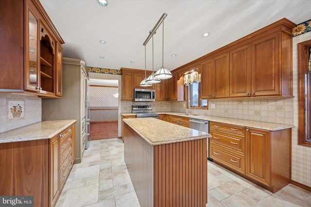 kitchen with stainless steel appliances, a center island, light stone countertops, brown cabinetry, and glass insert cabinets