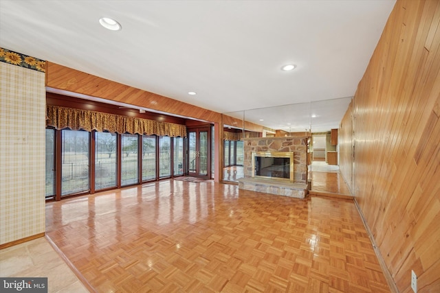 unfurnished living room with wooden walls, baseboards, a fireplace, and recessed lighting